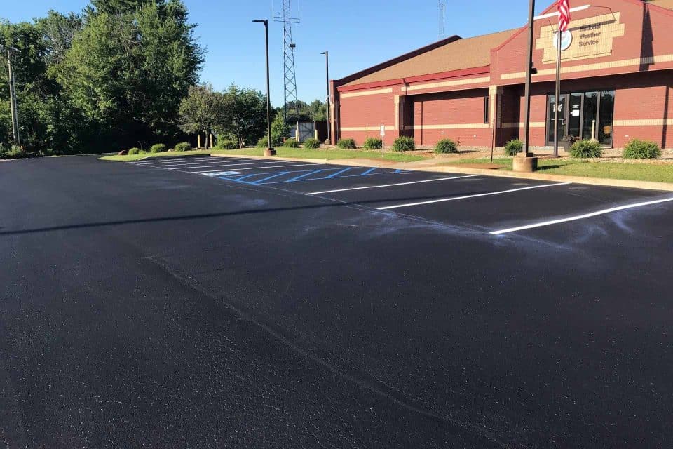 Well-kept parking lot with lined spaces by a red brick building.