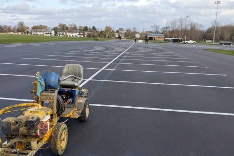 Freshly painted lines in an empty parking lot with a line marking machine.