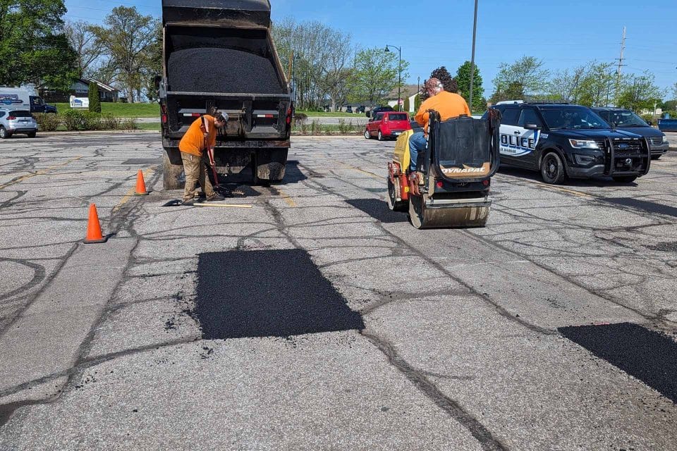 Super Seal team repairs potholes with a dump truck and roller.