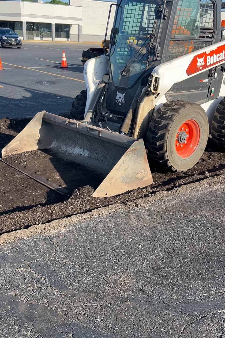 Sealcoating vehicle smoothing asphalt in a parking lot.