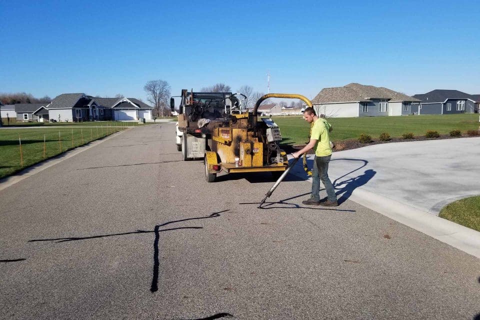 Contact worker for super seal asphalt crack filling on a residential street.