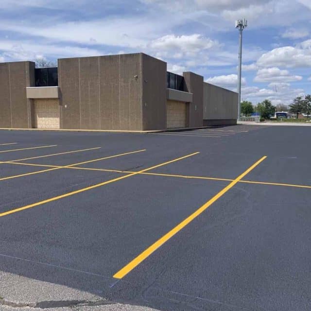 Empty parking lot with freshly painted yellow lines near a large building.