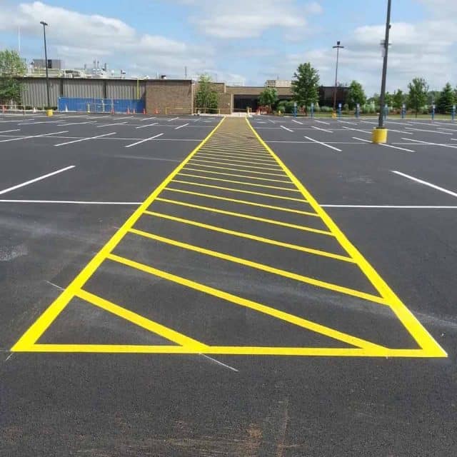 Empty parking lot with bright yellow diagonal lines painted on the pavement.