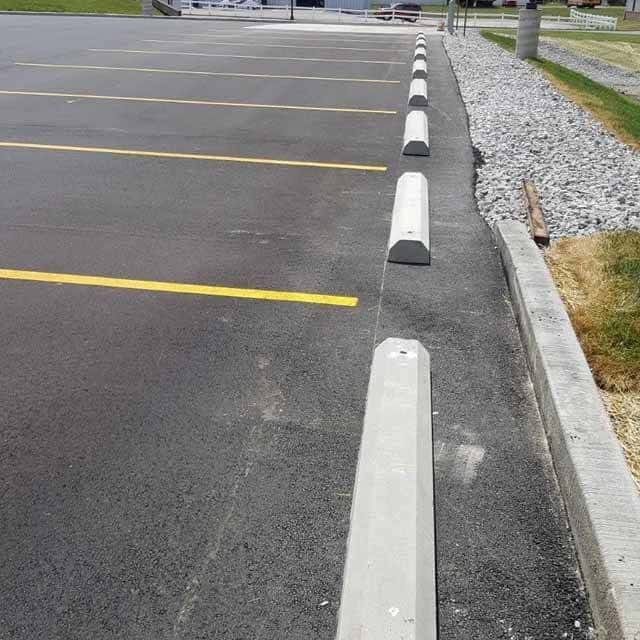 Parking lot with nine concrete wheel stops in a row.