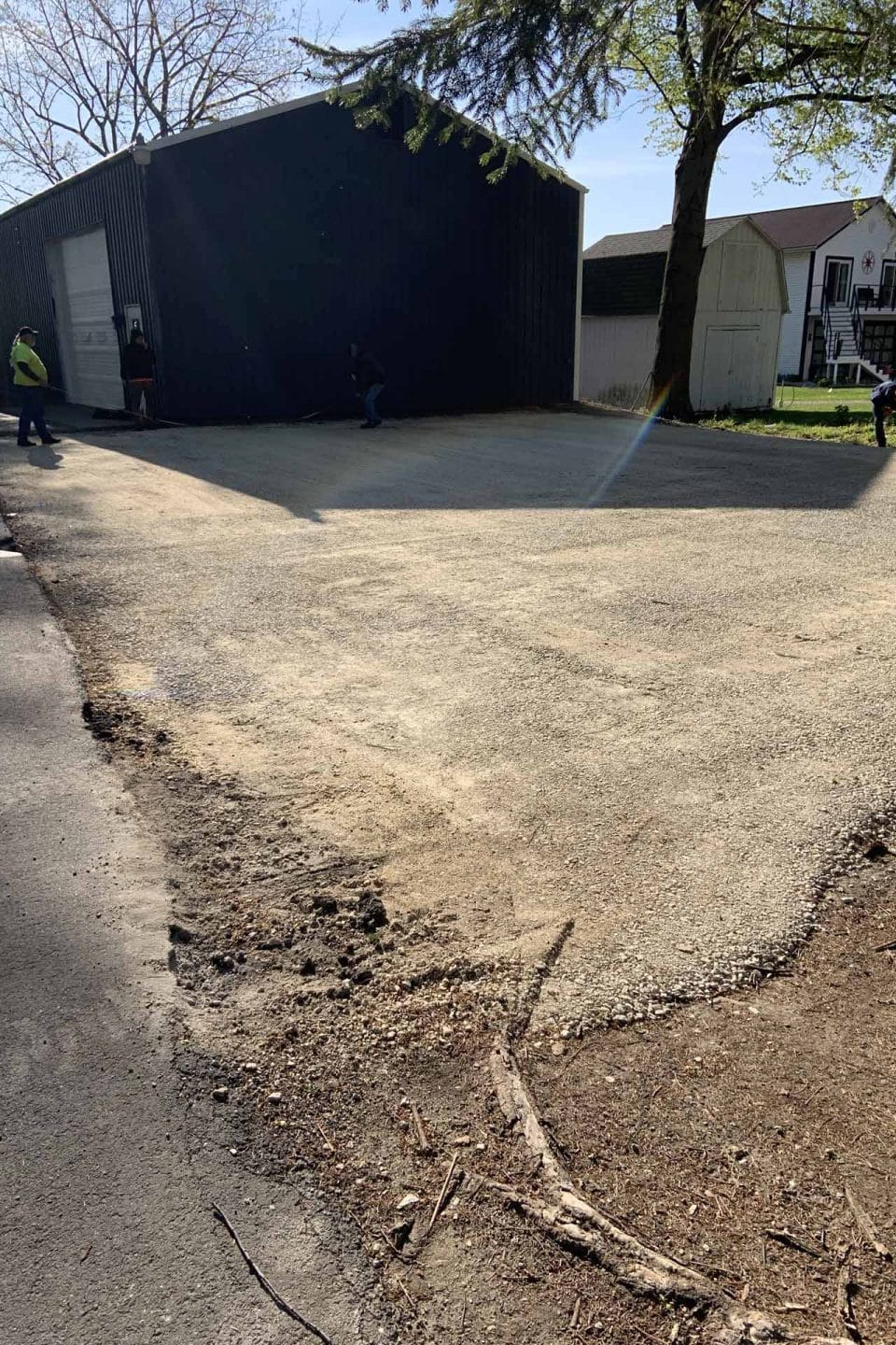 Wide driveway with gravel surface in front of a large black building.