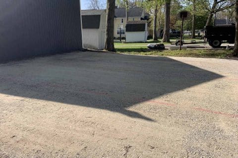 Gravel driveways wind through a residential area with buildings and trees.