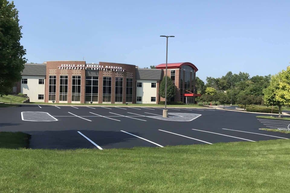 Large brick community center with a sealcoated, empty parking lot on a sunny day.