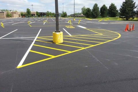 An empty parking lot with yellow markings and a pole in the center.